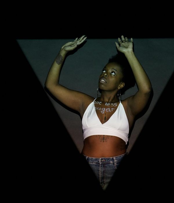 Woman in a dynamic cardio pose against a dark background with saffron light.